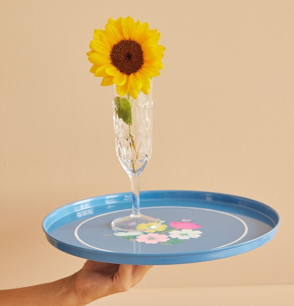 Emaljbricka Blå Med Blommor från Rice hålls i en hand