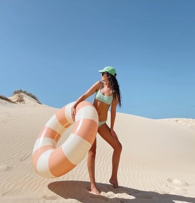 Kvinna med Badring Peach Daisy - Petites Pommes på sanddyn