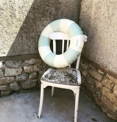 Badring Calile - Petites Pommes på sliten stol i stenmiljö