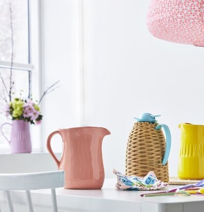 Termos från Rice omgiven av färgglada tillbringare och skedar