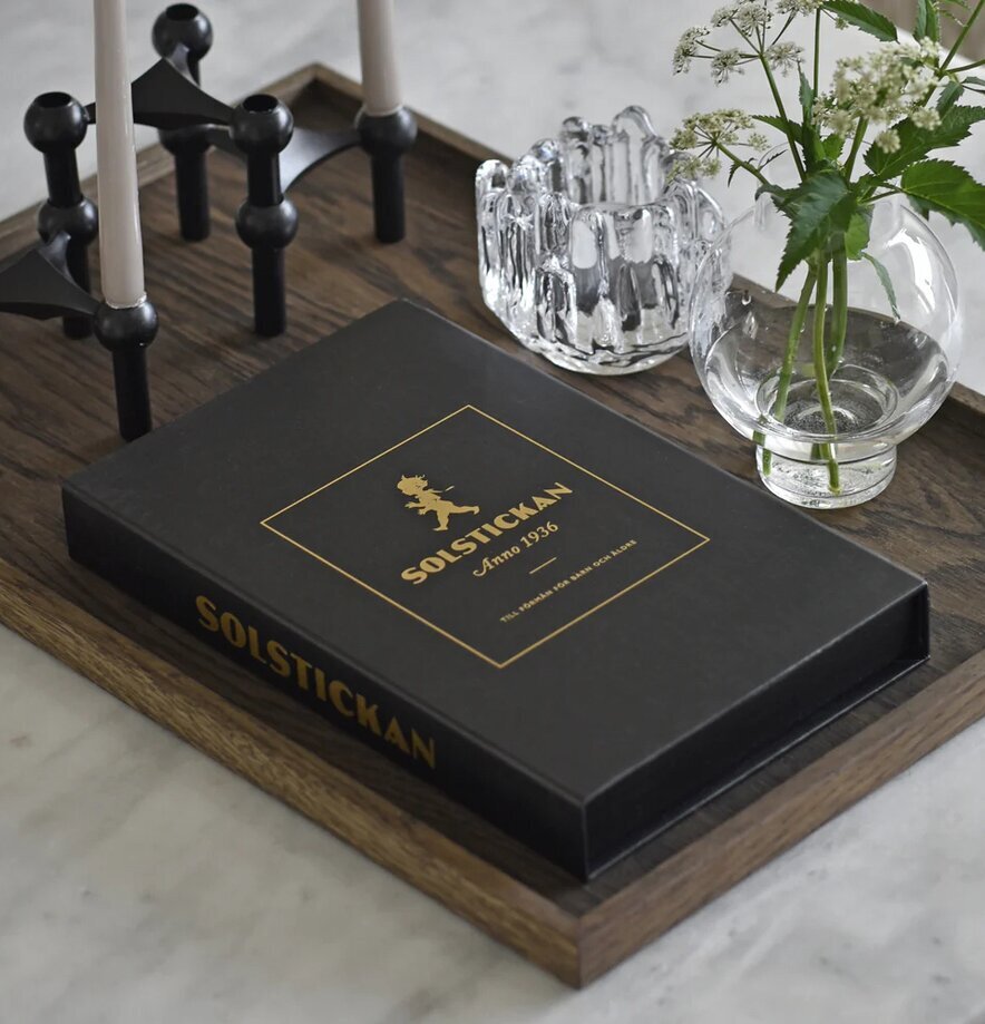 Solstickan Brandfilt Svart/Guld Tablebook på träbricka