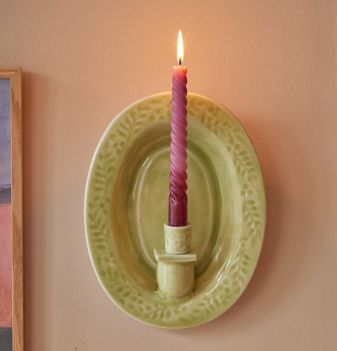 Väggljusstake Grön från Rice på neutral vägg med ljus