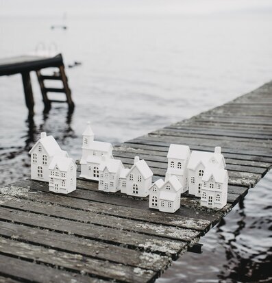 Bild av keramikby på träbrygga vid stilla vatten