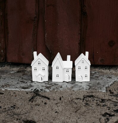 Bild av tre vita keramikhus med ljus och trävägg