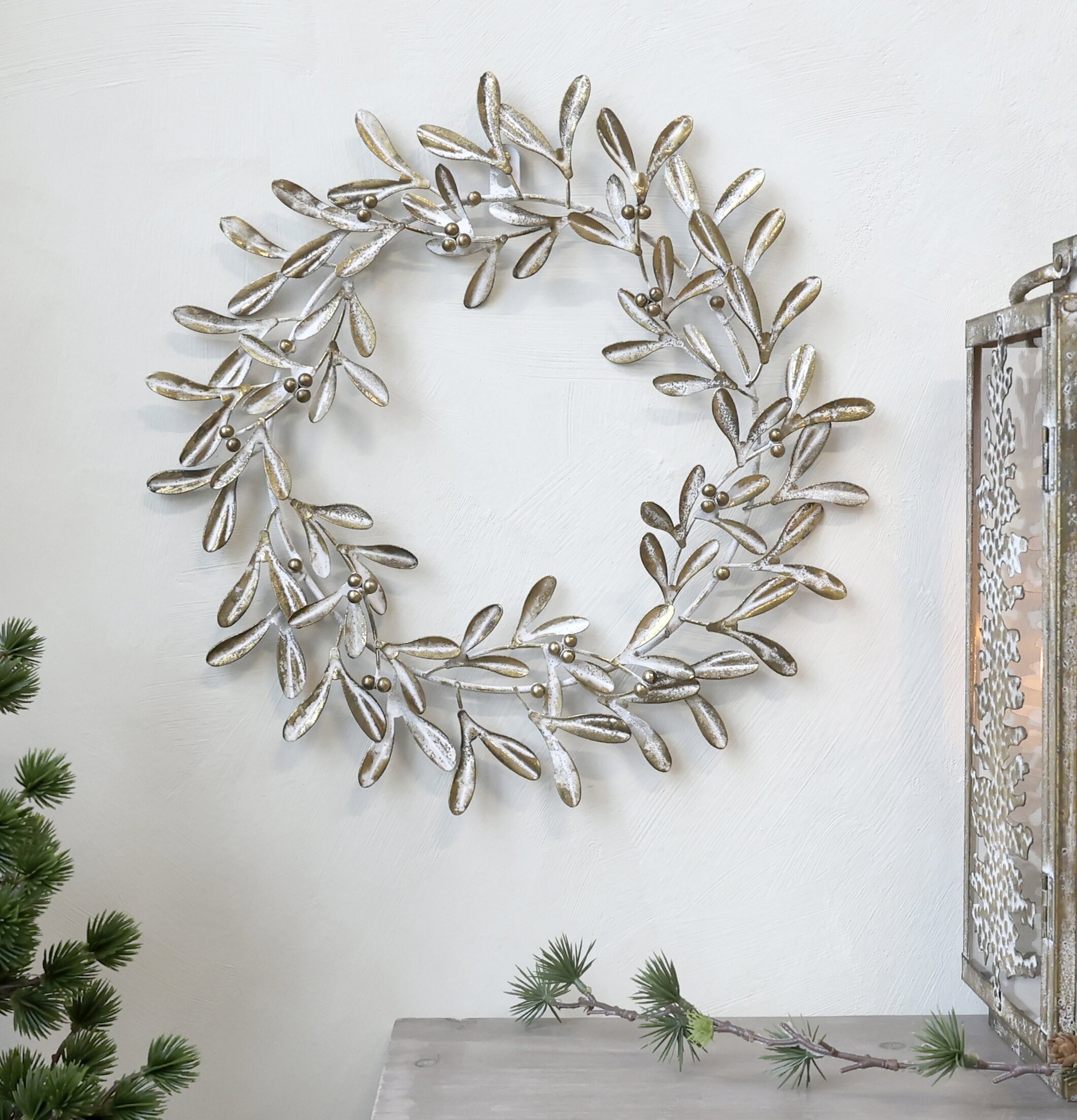 Krans Antik Mässing från Chic Antique på vit vägg med växt