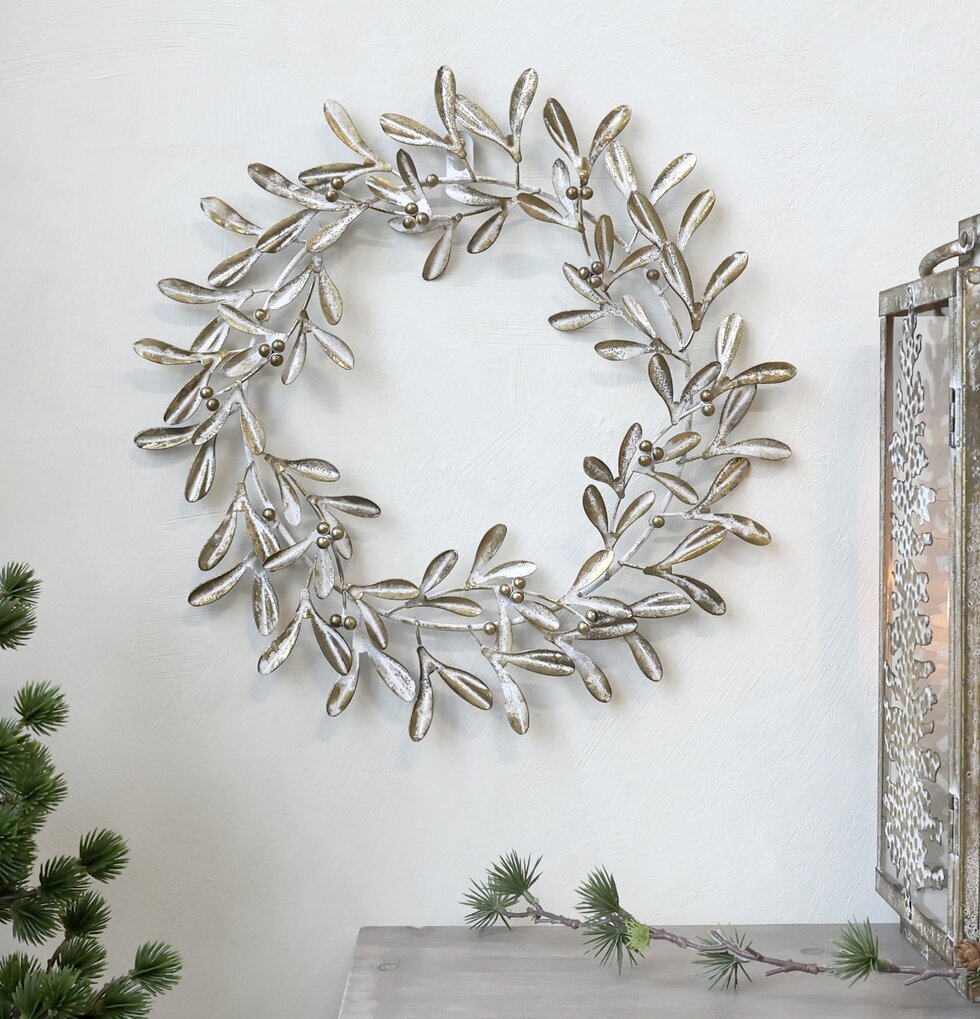 Krans Antik Mässing från Chic Antique på vit vägg med växt
