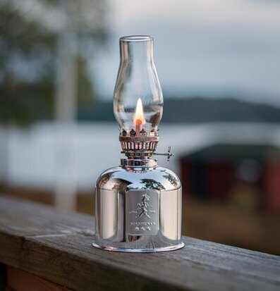 Fotogenlampa Silver från Solstickan på räcke vid sjö