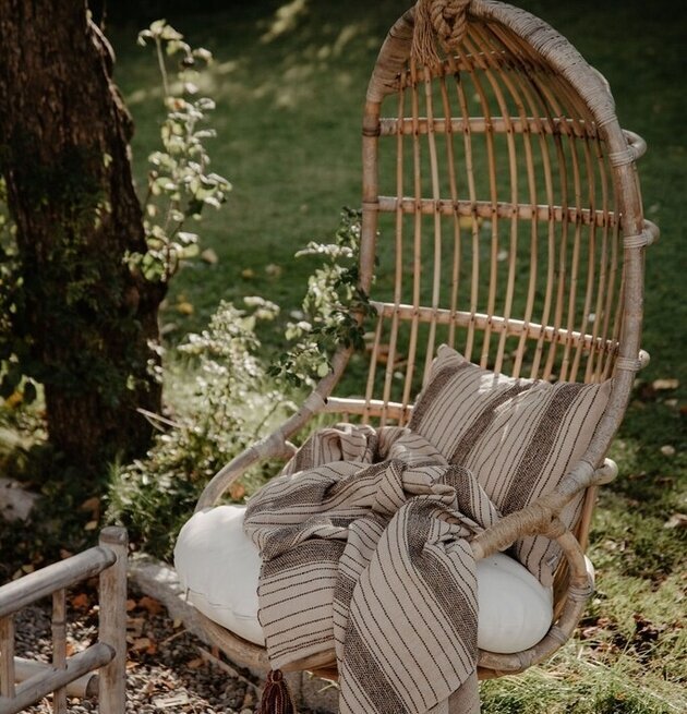 Pläd Tora Brun/Beige från Strömshaga i rottingstol utomhus