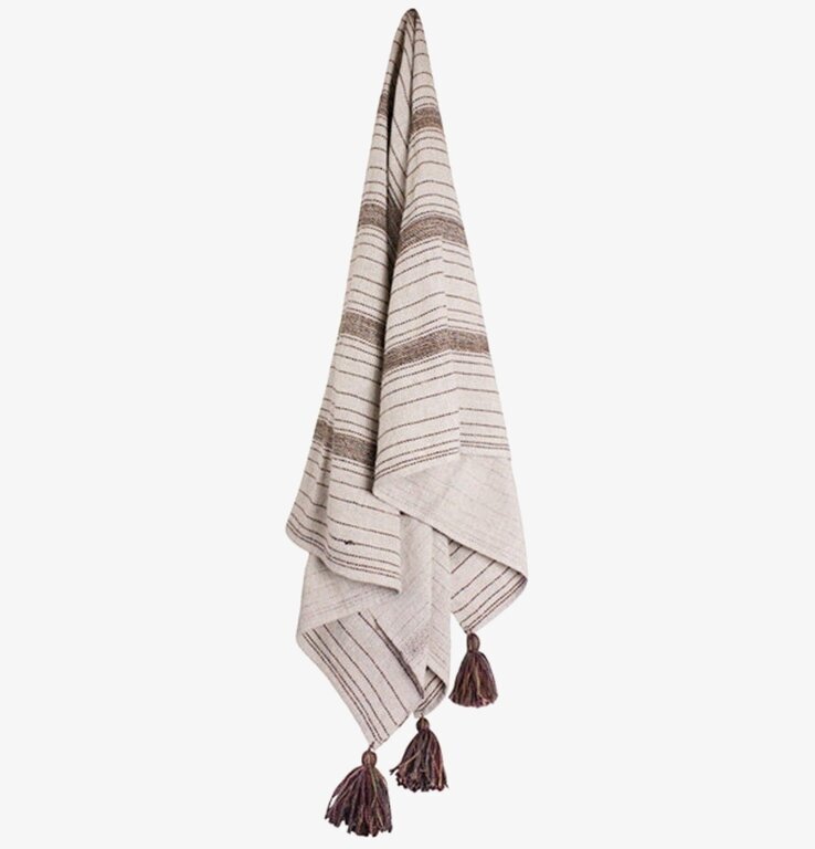 Pläd Tora Brun/Beige från Strömshaga hänger på vit vägg