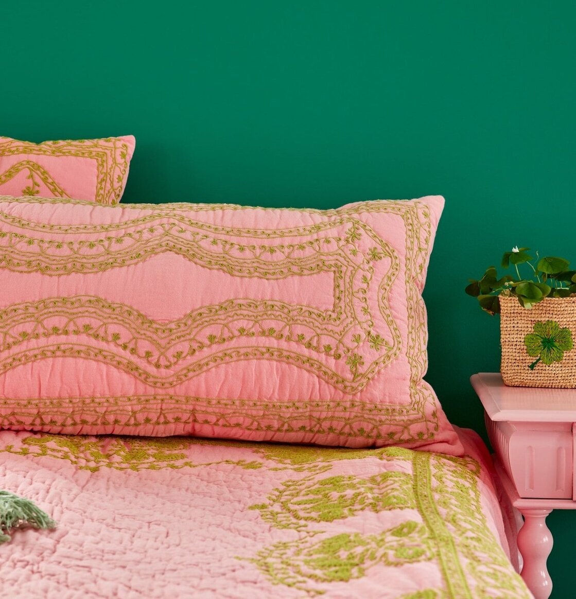 Prydnadskudde Rosa/Grön från Rice på en bäddad säng