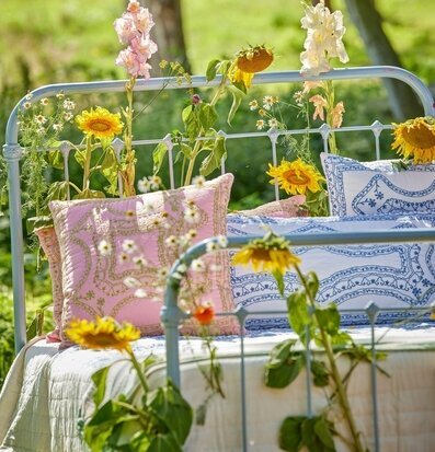 Prydnadskudde Rosa/Grön från Rice på järnsäng i trädgård