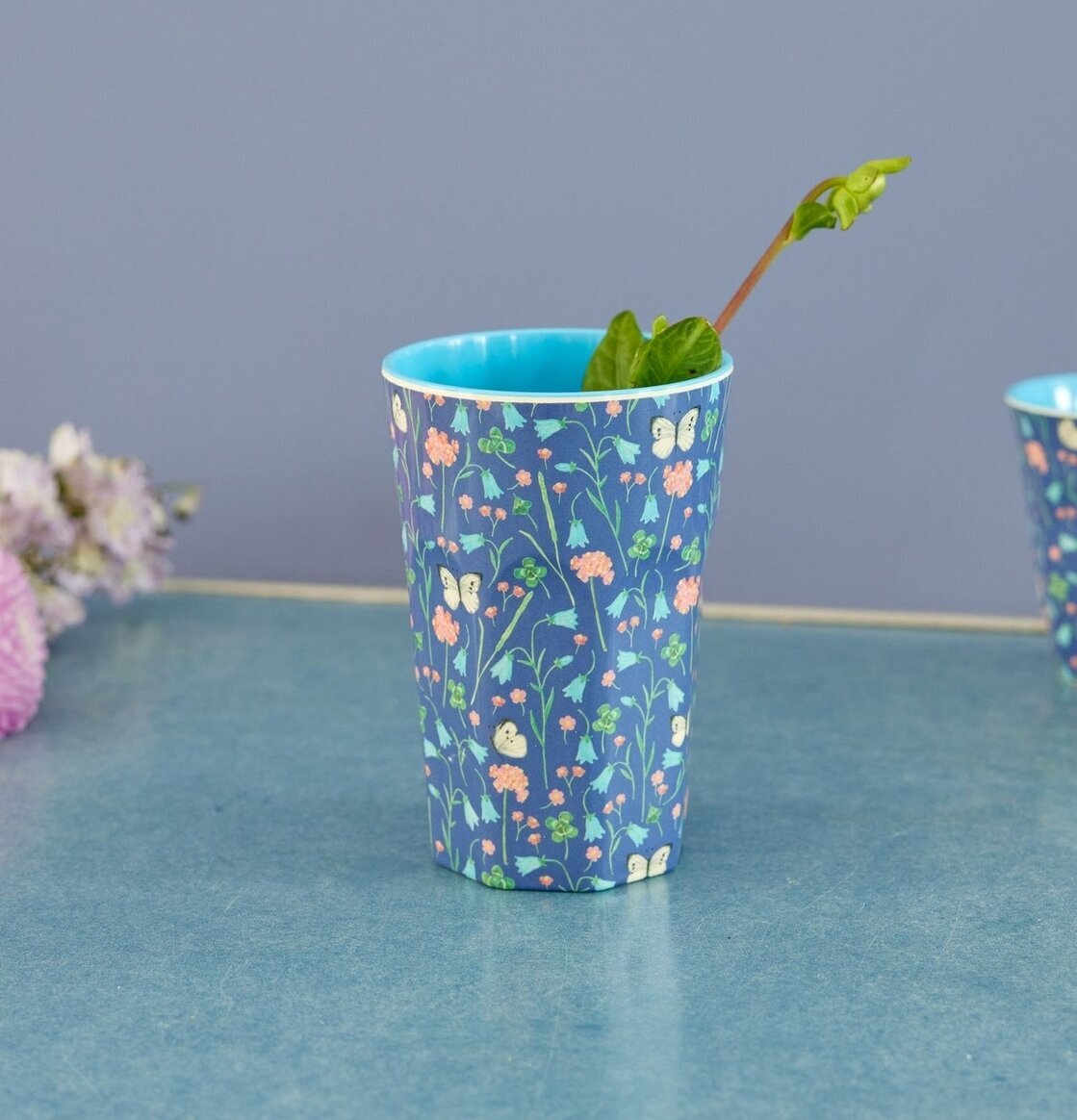 Foto av en mugg med fjärilar och blommor i fokus