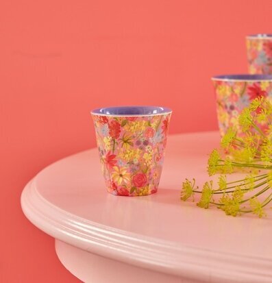 Bild av blommig mugg på pastellbord med växtdetaljer