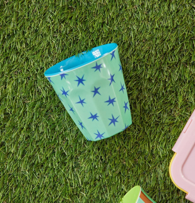 Bild av färgglada melaminmuggar på gräsmatta