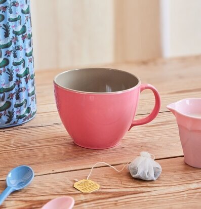 Bild av rosa mugg på rustikt bord med färgglada detaljer