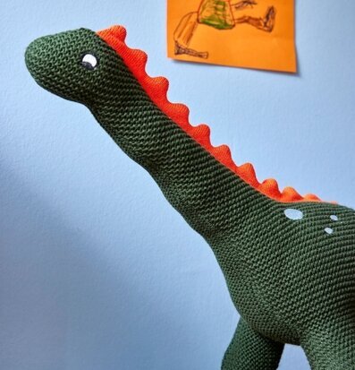 Prydnadskudde Dinoasurie från Rice på träyta och blå vägg