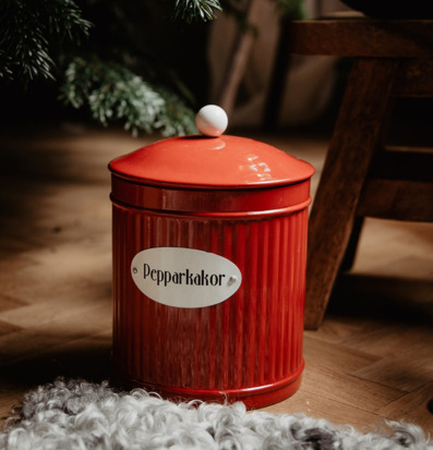 Bild av röd plåtburk med pepparkakor i hemtrevlig miljö