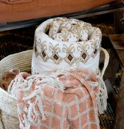 Pläd Terrakotta från Chic Antique i en korg med textilier