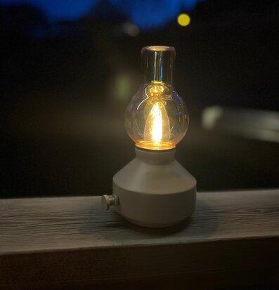 Bordslampa Glimt Sand/Amber från PR Home på träbalk utomhus