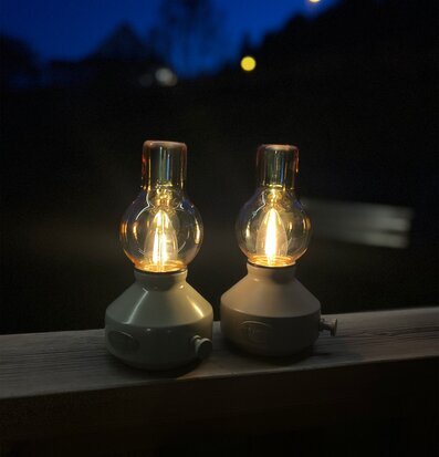 Bordslampa Glimt Sand/Amber från PR Home på trästaket i skymning