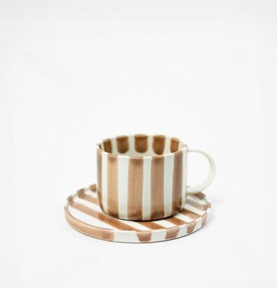 Foto av elegant kopp med fat i randigt mönster