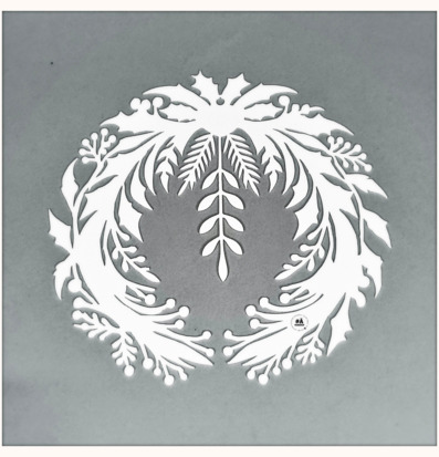 Bild av intrikat designad vit julkrans med plåtdetaljer