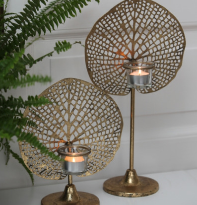 Bild av elegant ljushållare och grön ormbunke i hemmet