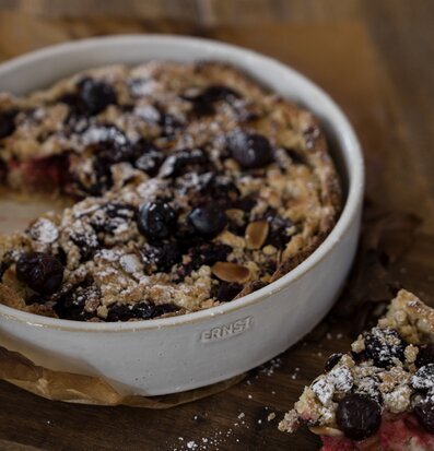 Bild av rund ugnsform med paj på rustik träbräda