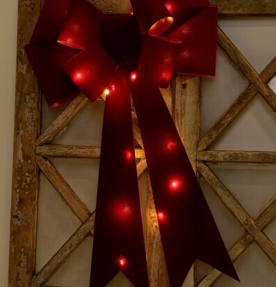 Bild av röd rosett med LED-ljus på rustik träram