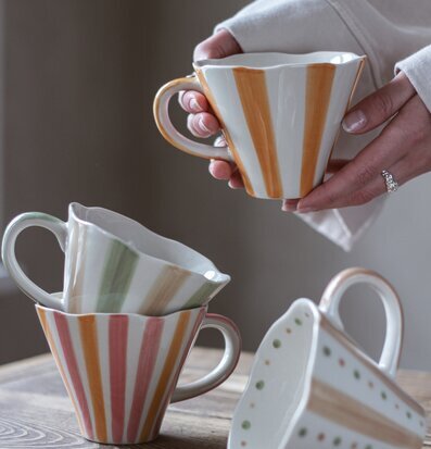 Bild av fyra keramikmuggar med livfullt randmönster