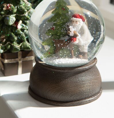 Bild av snöglob med tomte och rådjur i vinterskog