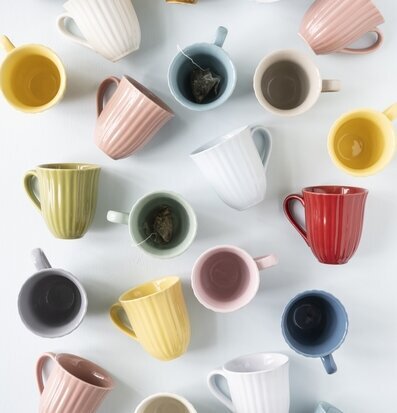 Bild av färgglada muggar på ljus bakgrund med te-påsar