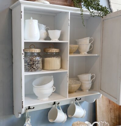 Foto av stilrent väggskåp med porslin och glasartiklar