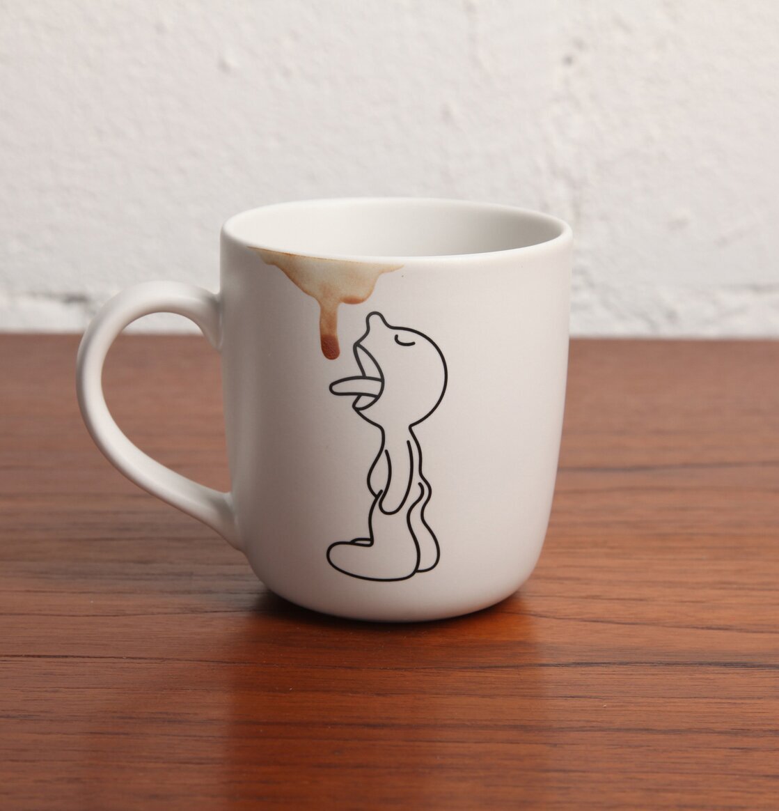 Mugg Mr.P Lick från Propaganda på träbord med ljus bakgrund