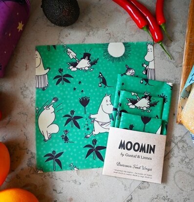 Bild av färgglad bivaxduk med Muminmotiv och matvaror