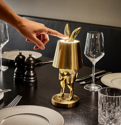 Bild av elegant bordslampa i glänsande guld på dukat bord
