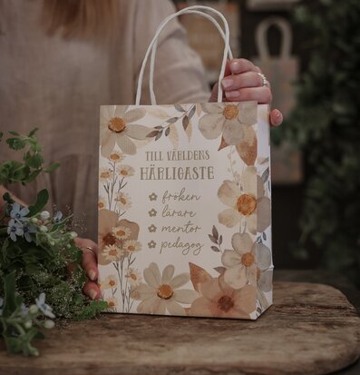 Bild av dekorativ gåvopåse med blommönster och text