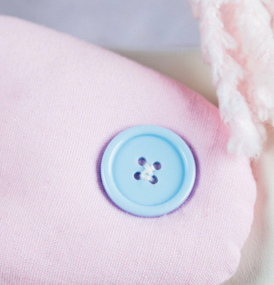 Bild av rosa tyg med ljusblå knapp och fluffig textur
