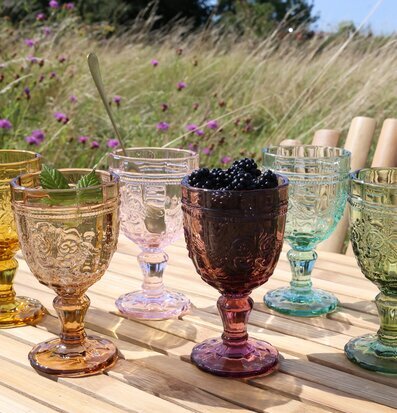 Bild av färgglada vinglas på träbord i somrig miljö