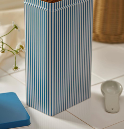 Bild av plåtburk med blåvita ränder och dekorativa detaljer