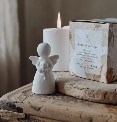 Bild av en lugnande scen med ängelfigur och ljus