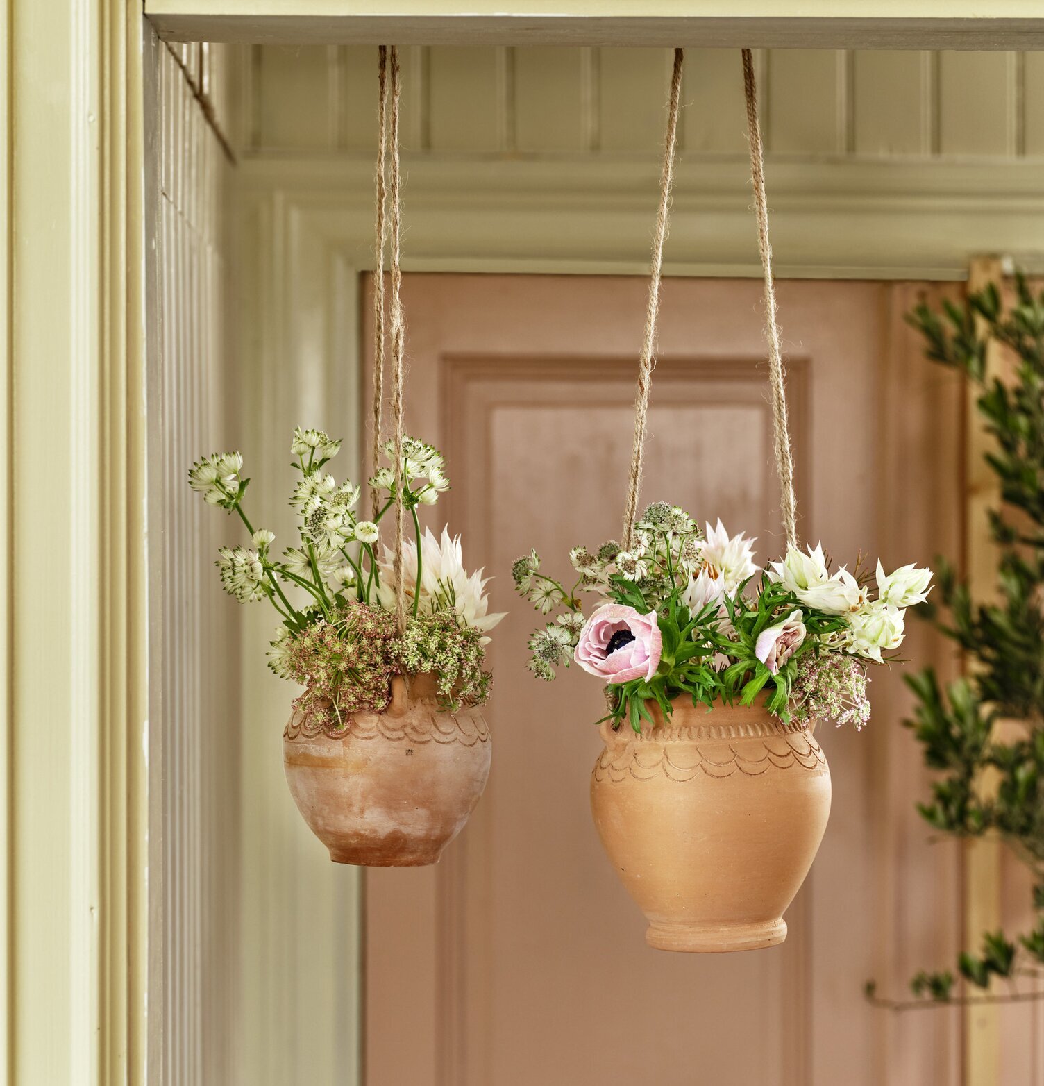 Bild av eleganta hängande krukor i terrakotta och jute