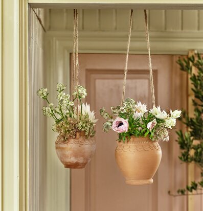 Bild av eleganta hängande krukor i terrakotta och jute
