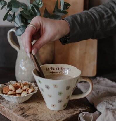 Bild av hemtrevlig scen med keramikmugg och naturmaterial