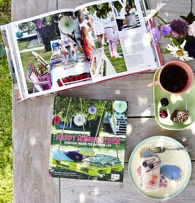 Bok Happy Home Outside från Rice på träbord med fika