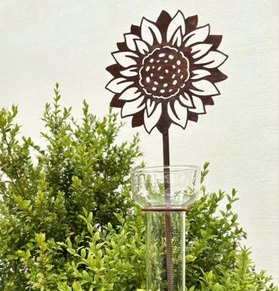 Foto av regnmätare med solrosdesign i trädgårdsmiljö