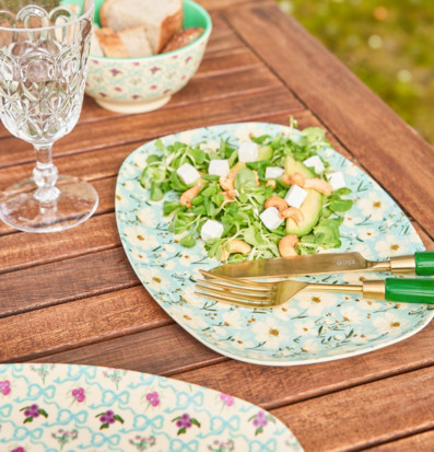 Bild av somrig utomhusdukning med blommig tallrik och sallad