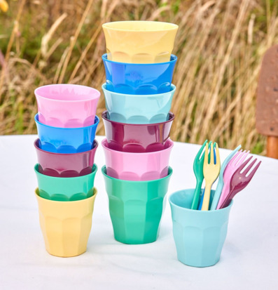 Bild av färgglada melaminmuggar och plastbestick utomhus