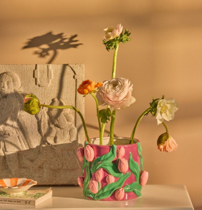 Bild av stilleben med blomkruka, snittblommor och stenrelief