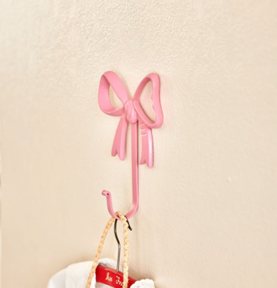 Bild av rosa väggkrok formad som rosett med hängande plagg